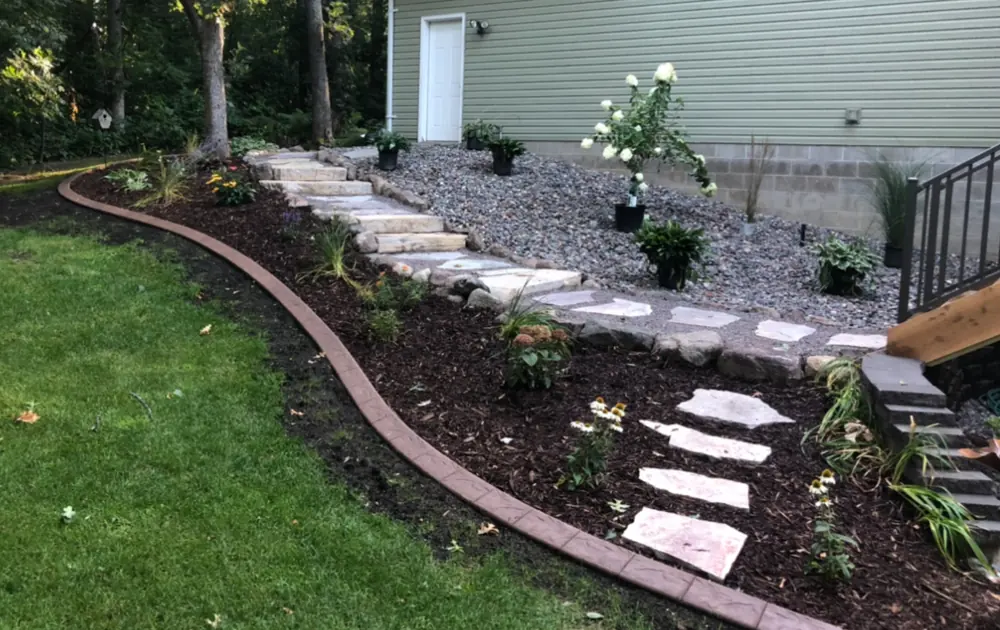 Curved brick edging, stepping stones and mulched beds along a lawn