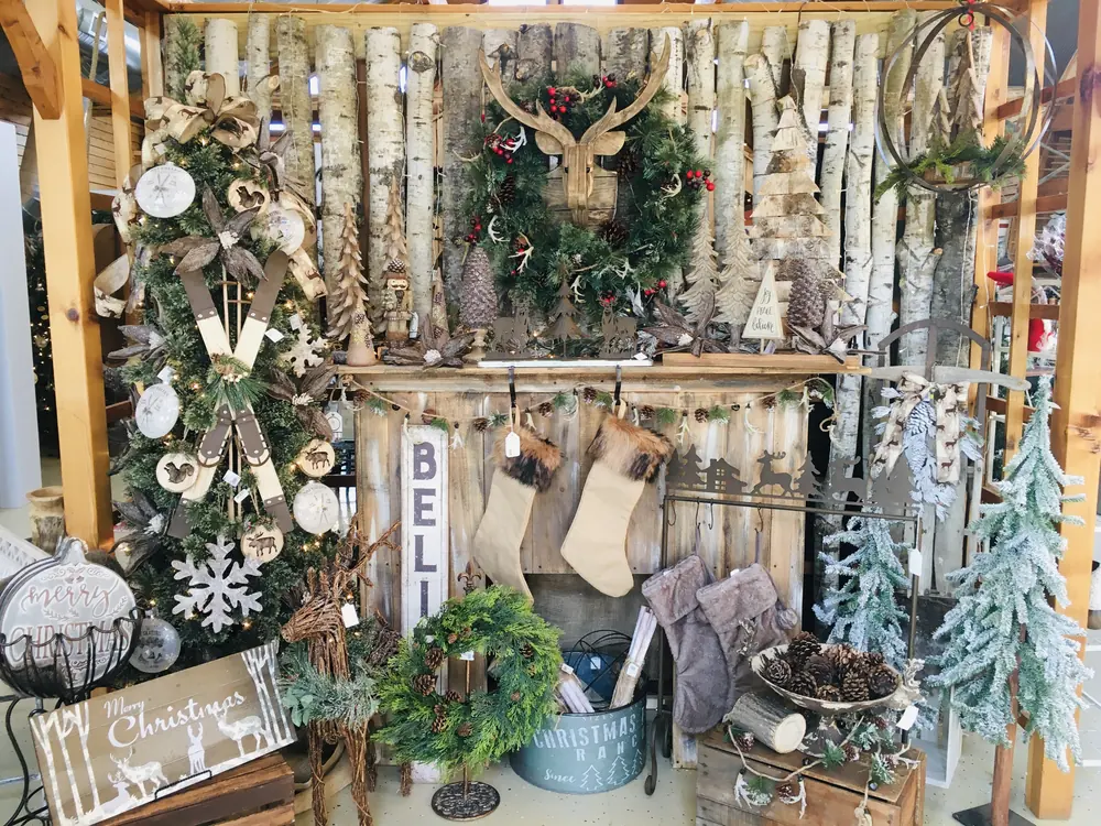 Gift shop corner with a birch-trunk backdrop, wreaths, stockings and a Christmas sign